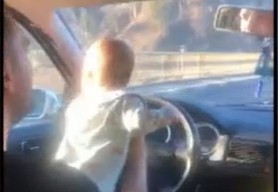 VIDEO // Gestul inconștient: Conduce mașina în timp ce ține un bebeluș pe volan. Filmarea ar fi fost făcută de mama copilului